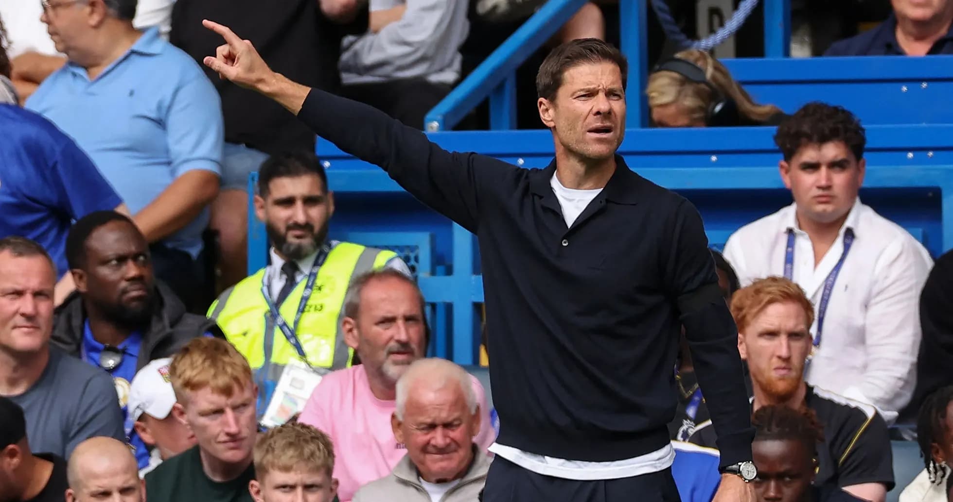 Coach gesturing during a match with spectators behind