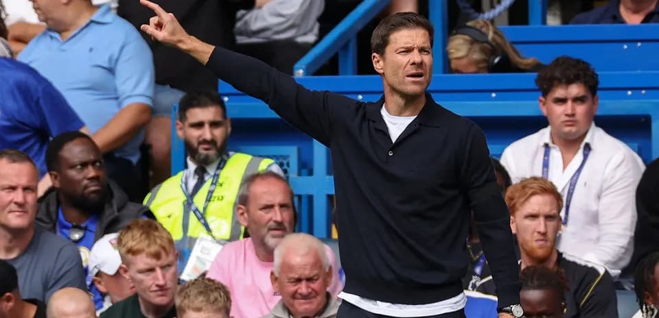Coach gesturing during a match with spectators behind