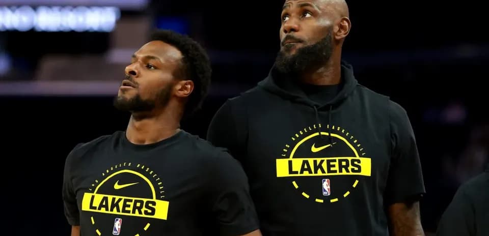 Two Lakers players in warm-up gear on court