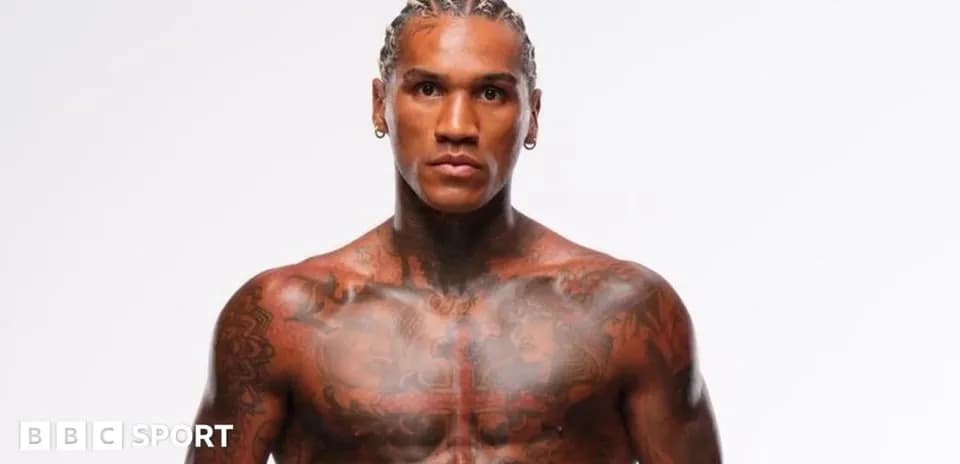 Athlete posing shirtless with tattoos and braids