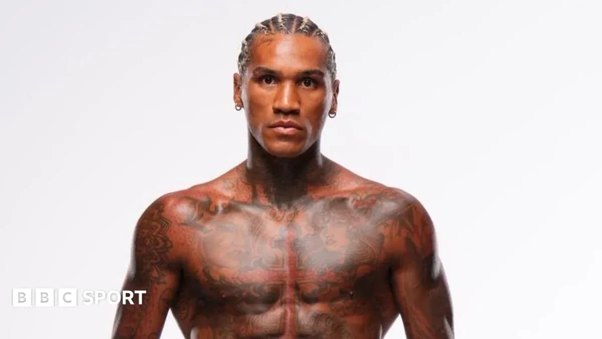 Athlete posing shirtless with tattoos and braids