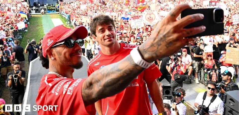 Two drivers taking a selfie with fans in background