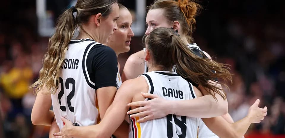 Four basketball players celebrating in team uniforms