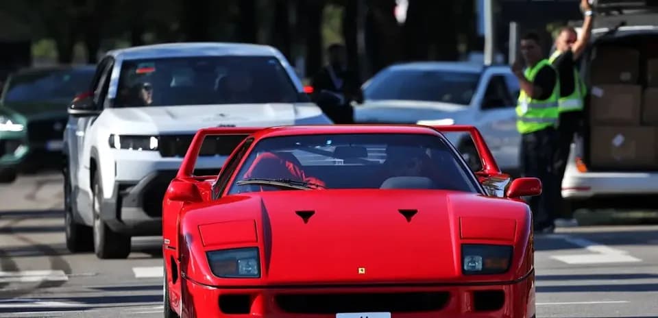 Red sports car driving in busy street traffic