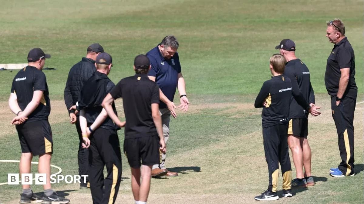Coaching staff discussing strategy on cricket field