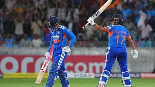 Indian cricketer celebrating while teammate walks off