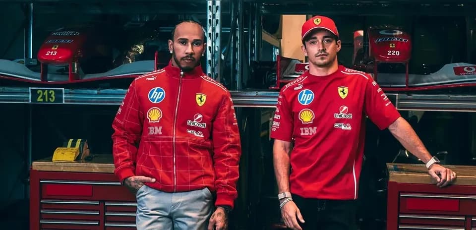 Two drivers in Ferrari team gear beside cars