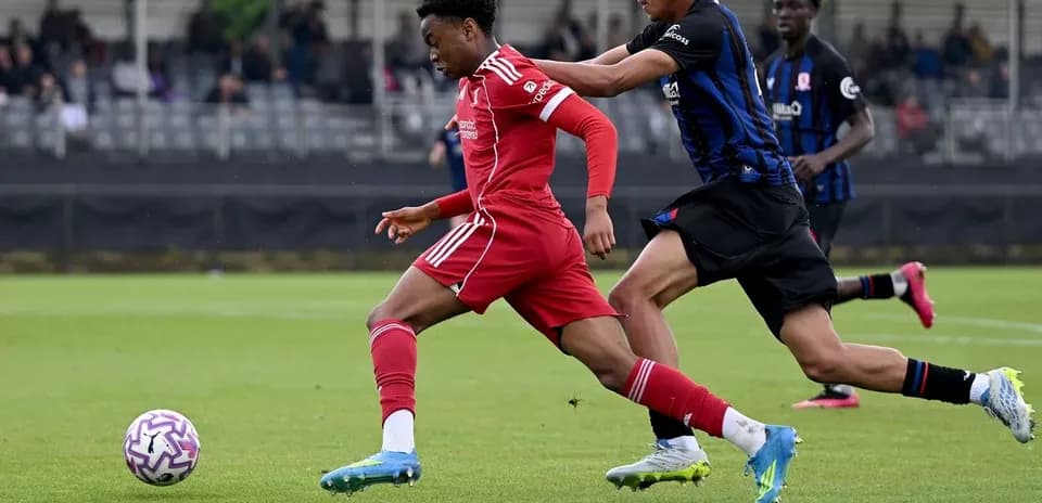Player in red shirt dribbling past opponent in blue