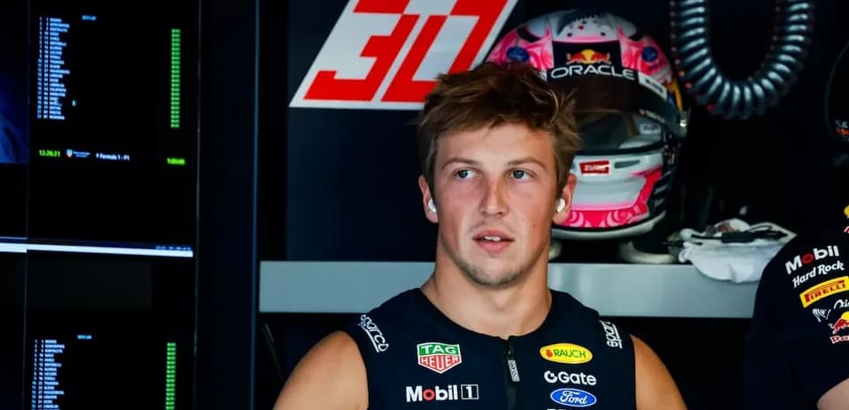 Driver in team garage with racing helmet behind