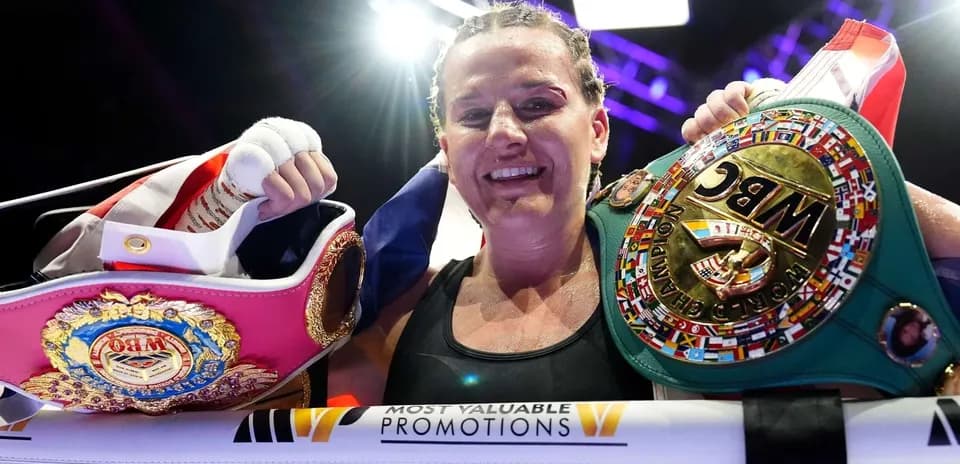 Boxer holding championship belts in the ring
