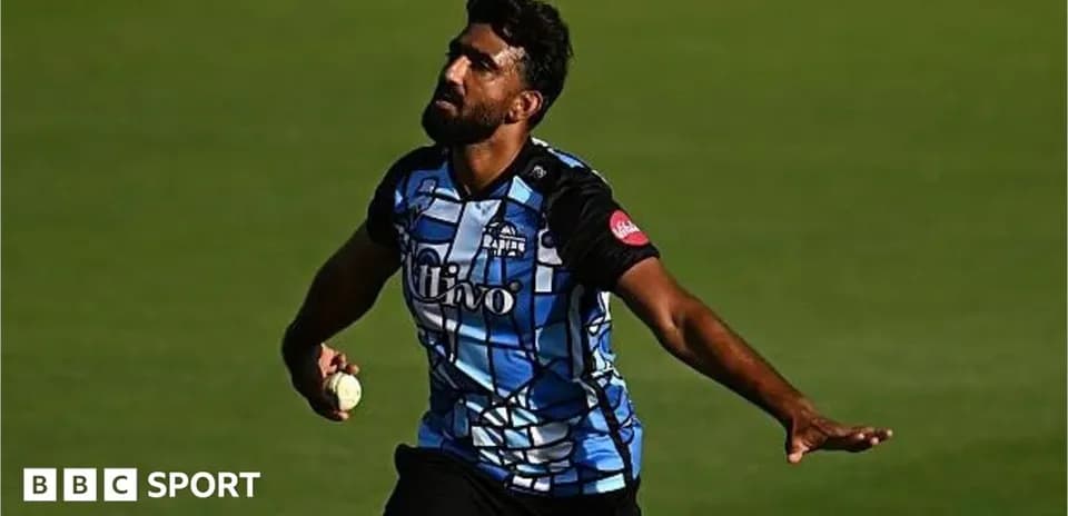 Cricketer bowling during a match in blue jersey