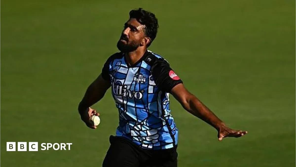 Cricketer bowling during a match in blue jersey