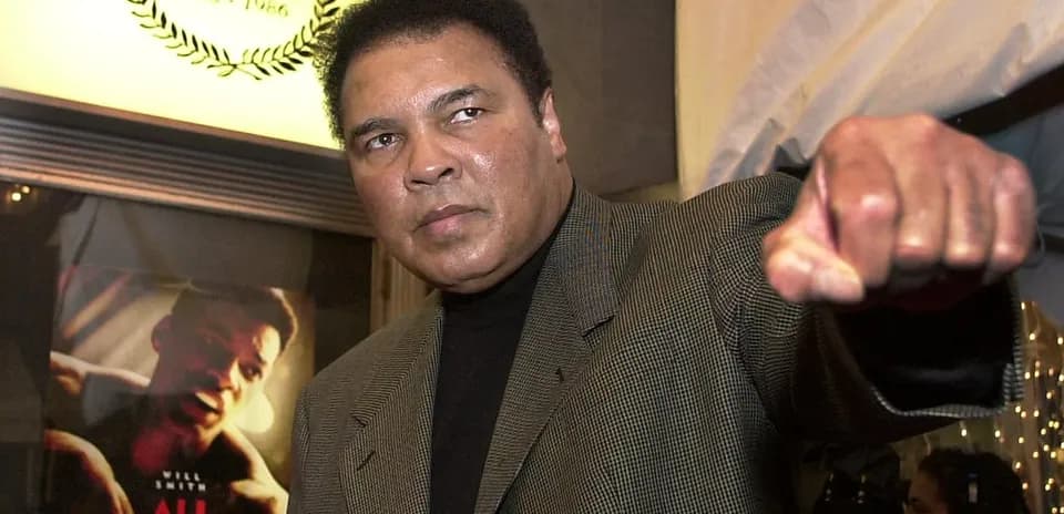 Man raising fist at event with movie poster behind