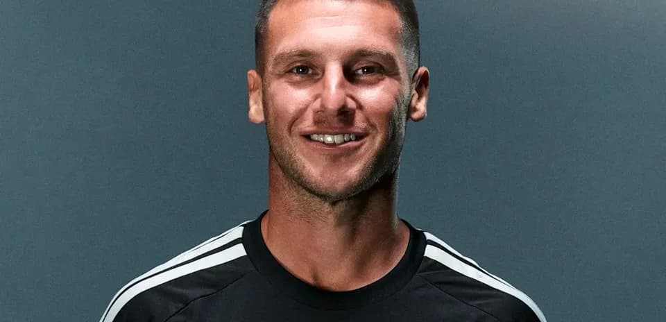 Player smiling in team training kit against backdrop