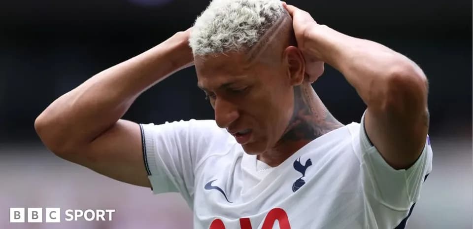 Player holding head during match, wearing Tottenham jersey