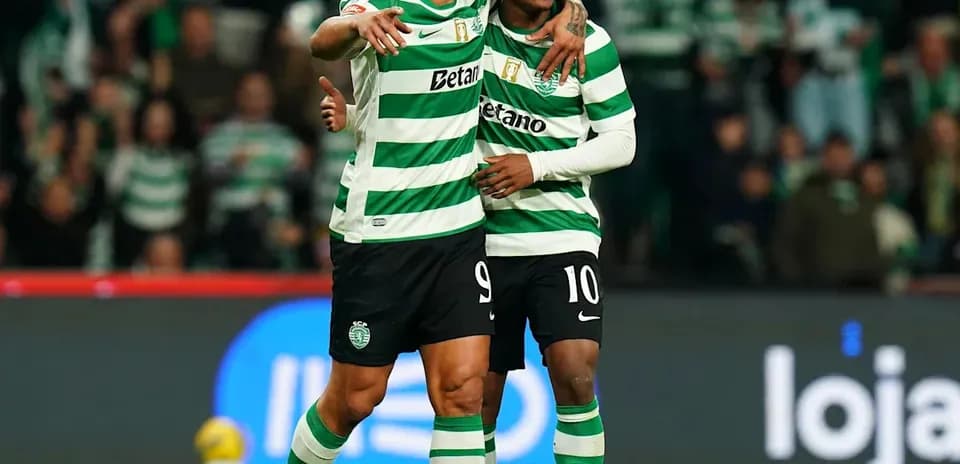 Two players celebrating on the pitch in team jerseys