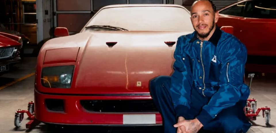 Person kneeling next to a red Ferrari in garage