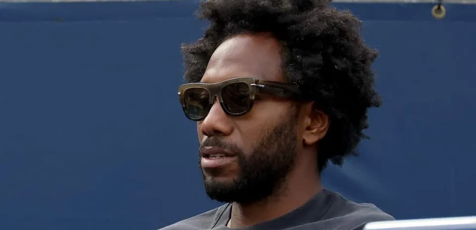 Man with sunglasses sitting on bleachers