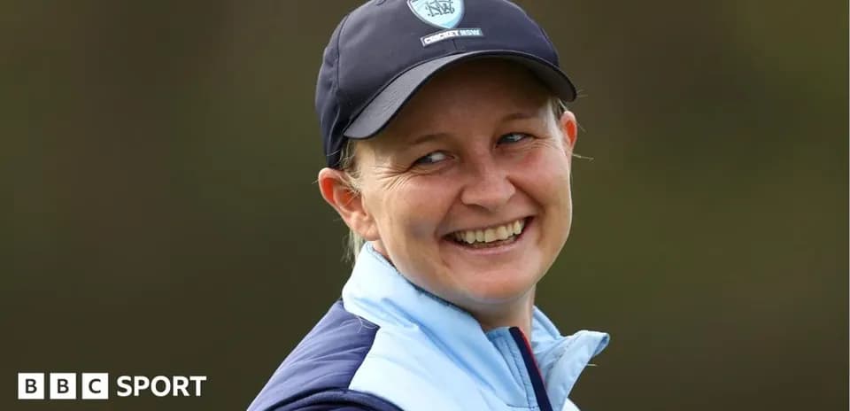 Smiling woman wearing a cricket cap and jacket