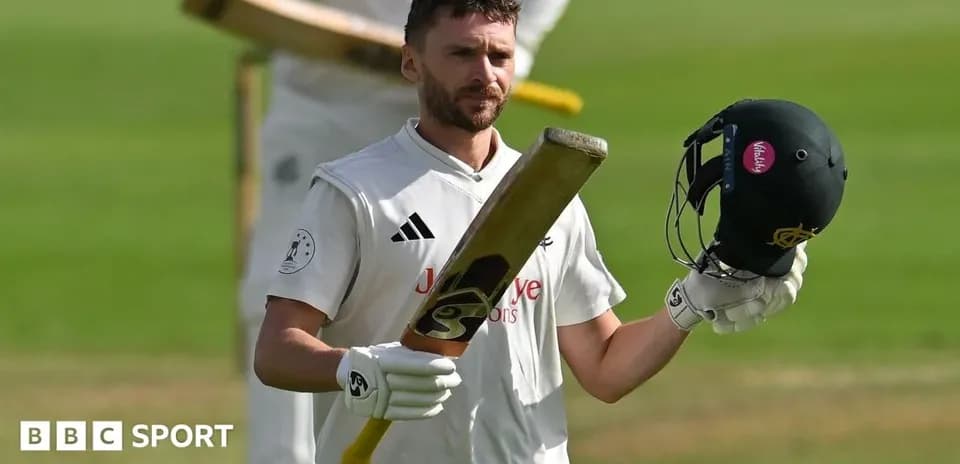 Batsman raising helmet and bat on cricket field