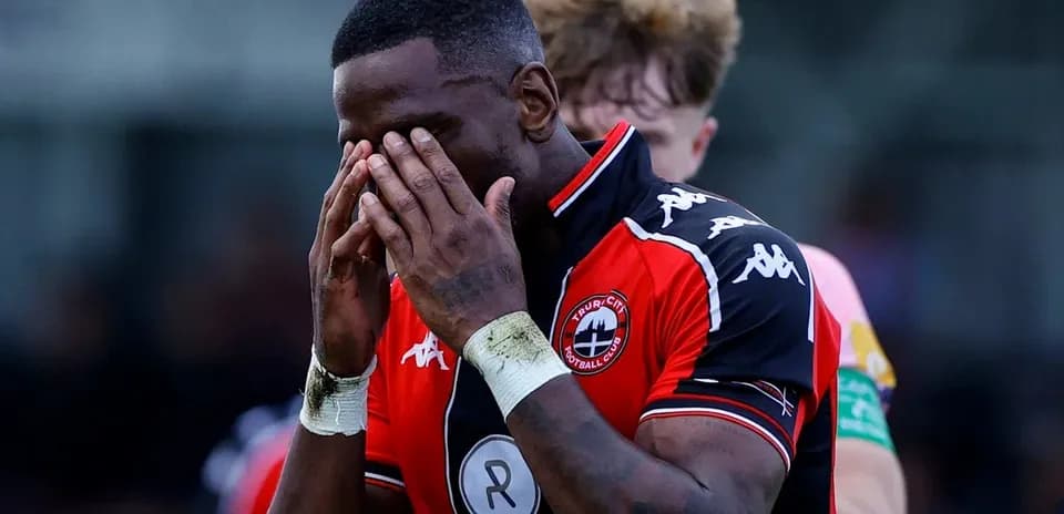 Player in red jersey holding face in disappointment