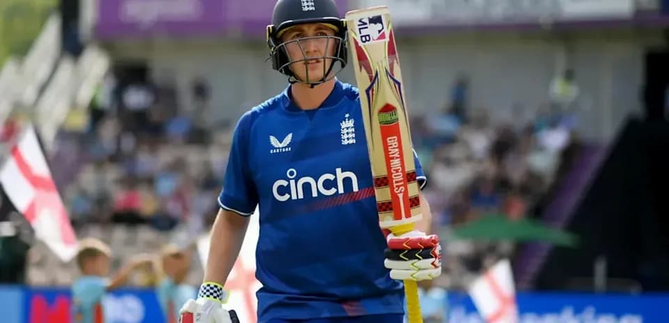 Cricketer in blue kit walking with bat