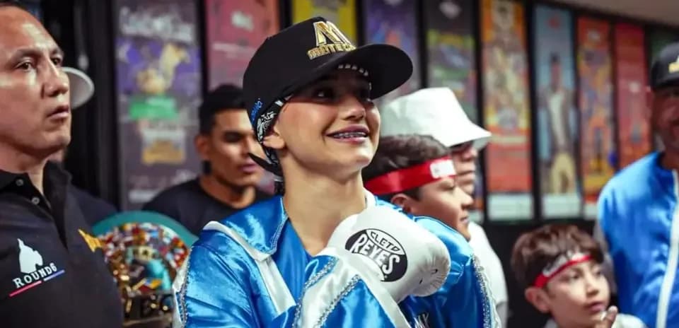 Young boxer smiling with gloves and team members
