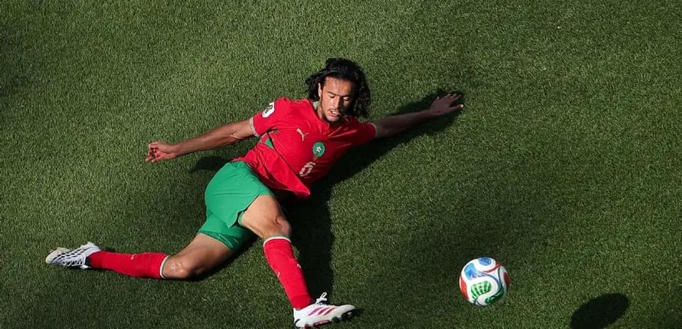 Moroccan player sliding on grass after ball
