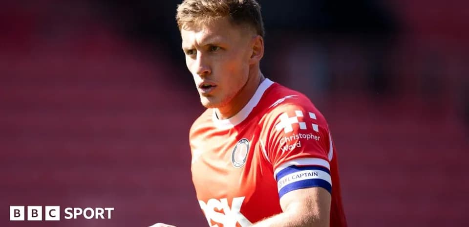 Player in red jersey with captain armband on field