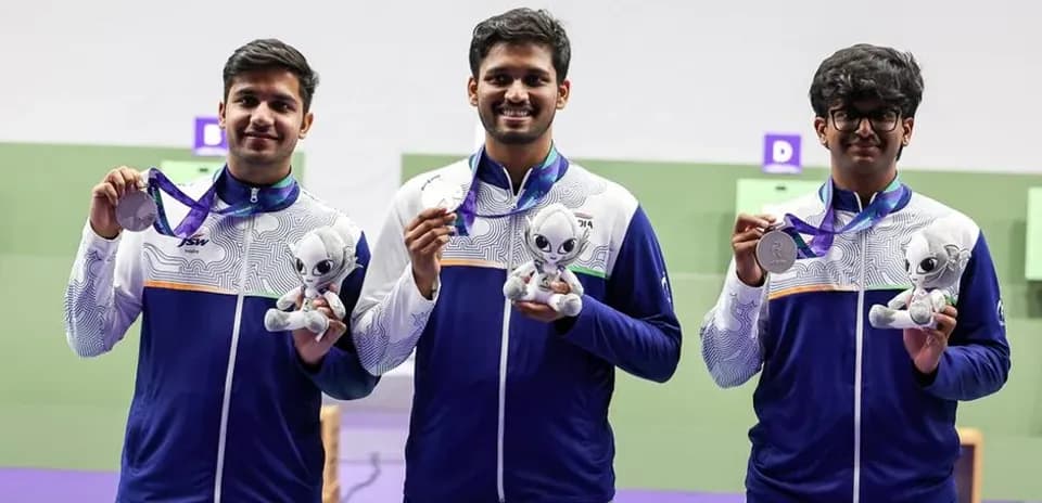 Three athletes holding medals and plush toys on podium
