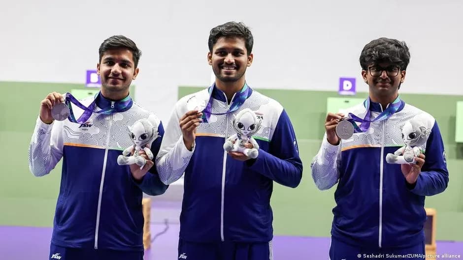 Three athletes holding medals and plush toys on podium