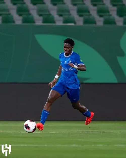 Player in blue kit dribbling ball on field