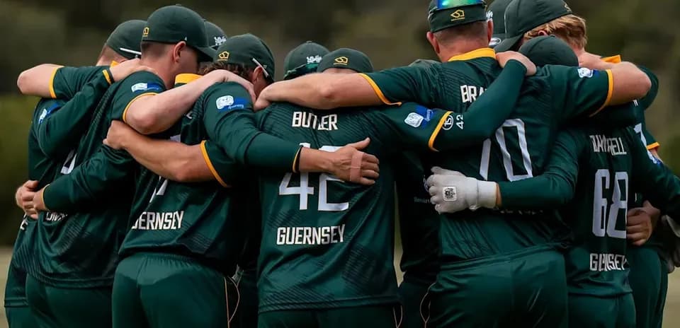 Cricket team huddled together in green uniforms