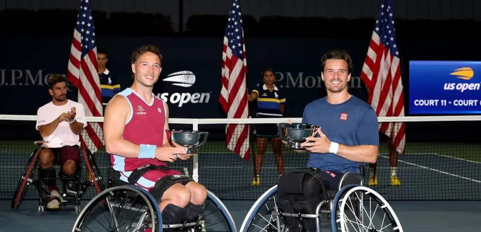 Two wheelchair tennis players holding trophies after match