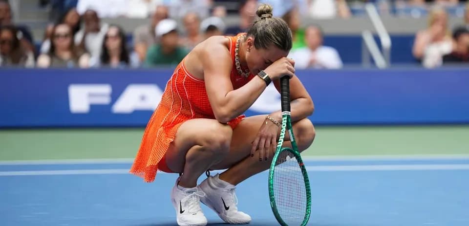 Tennis player kneeling on court holding racket