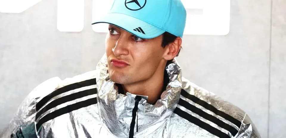 Driver wearing a silver jacket and blue cap