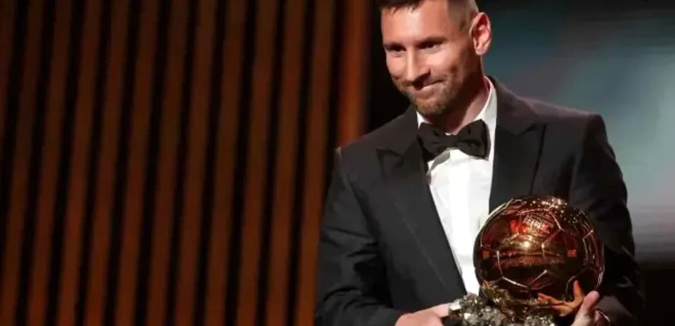 Player holding Ballon d'Or trophy on stage
