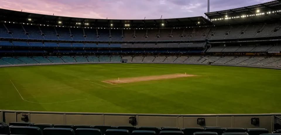Empty cricket stadium with pitch at dusk