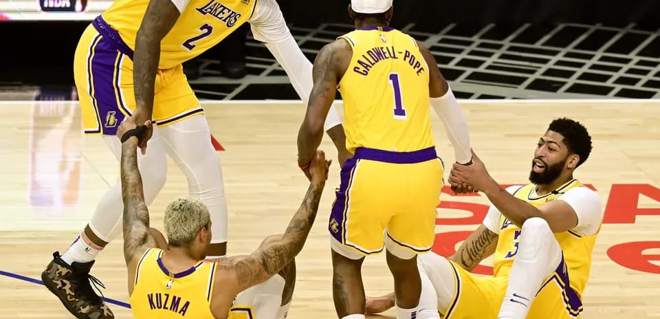 Lakers players helping teammates up from the court