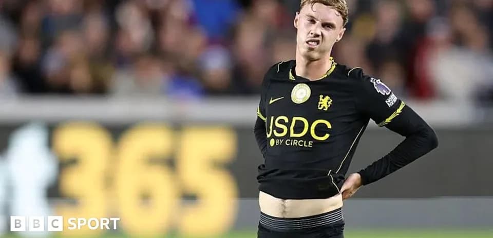 Player in black kit holding his stomach on field