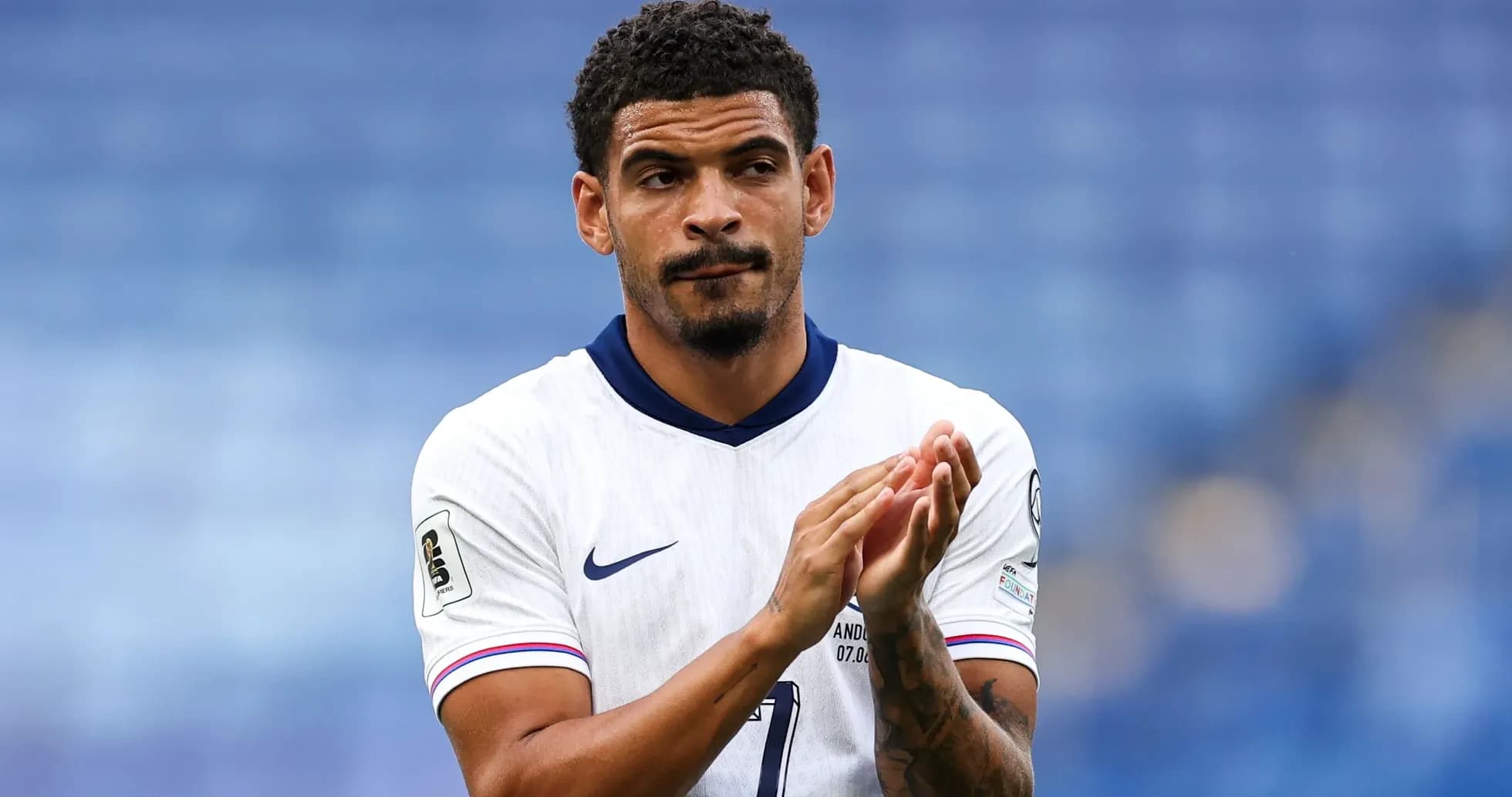 Player applauding in white football kit on pitch
