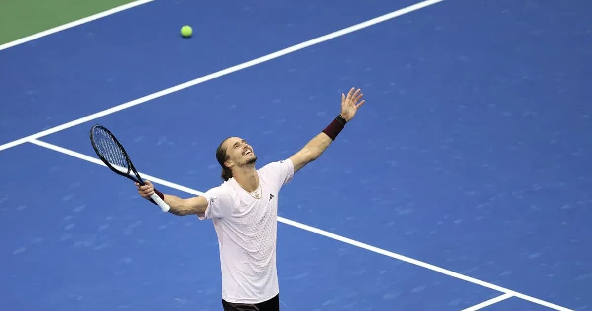 Tennis player celebrating on blue court with ball nearby