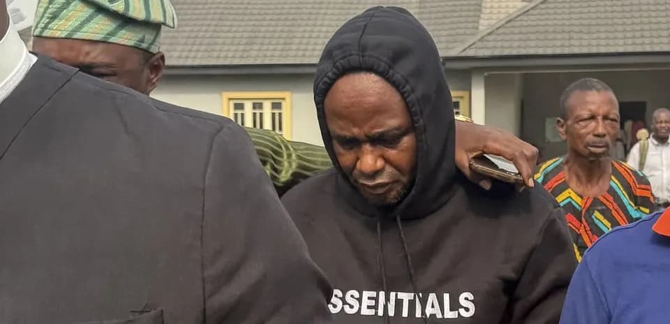Man in hoodie surrounded by onlookers outdoors