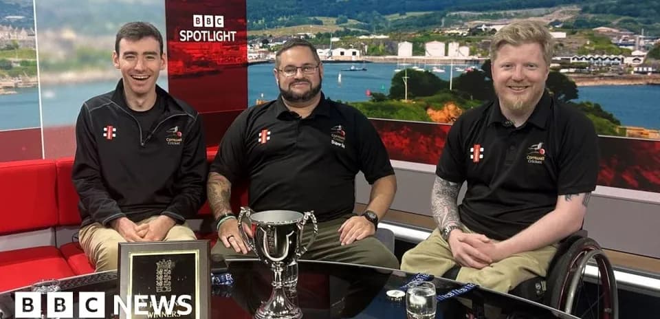 Three men posing with trophy on studio set