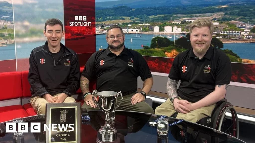 Three men posing with trophy on studio set