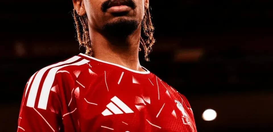 Player posing in red football kit with sponsor logo