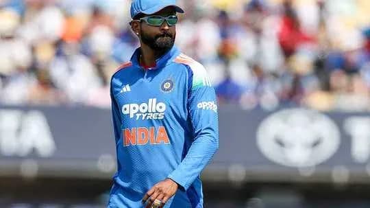Cricketer in blue uniform walking on field