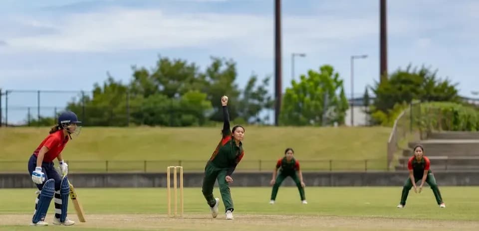 Bowler delivering ball with fielders in position