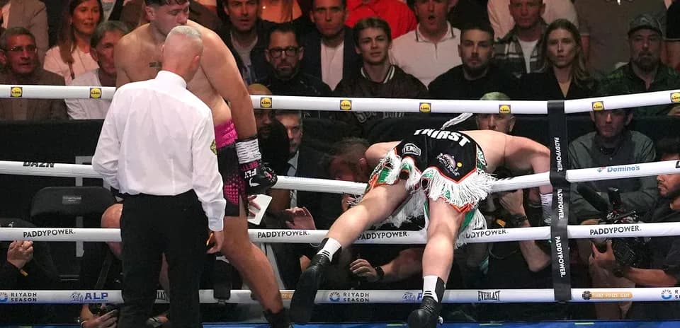 Boxer knocked down, referee checking on the fighters