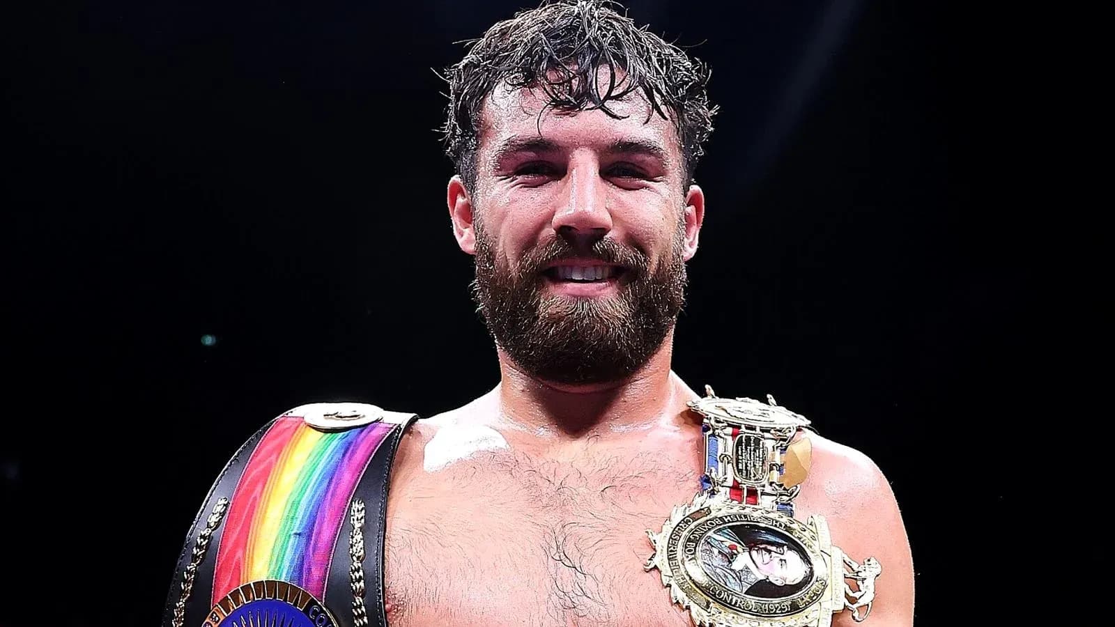 Boxer holding championship belts and smiling